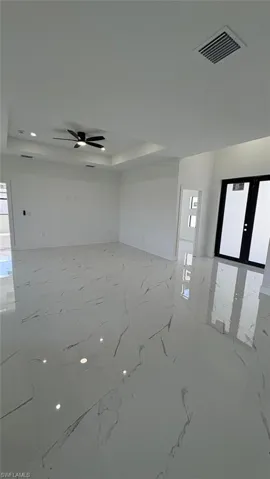 Unfurnished room with marble finish floor, visible vents, a tray ceiling, and french doors