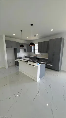 Kitchen with marble finish floor, decorative light fixtures, and gray cabinetry