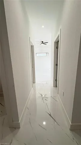 Hallway with marble finish floor, a textured wall, and baseboards
