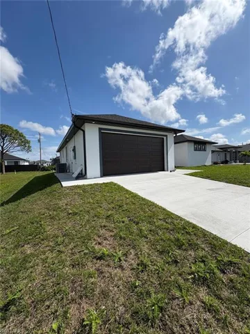 View of front of property with a garage, a front yard, concrete driveway, and stucco siding