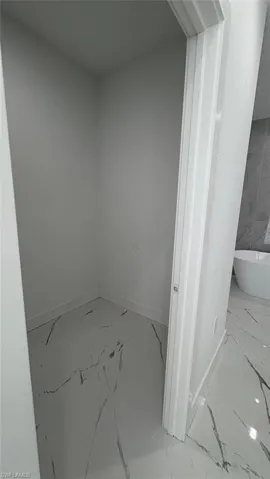 Full bathroom featuring a freestanding bath, marble finish floor, and baseboards