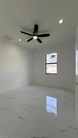 Empty room with marble finish floor, visible vents, a ceiling fan, and recessed lighting