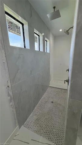 Bathroom with plenty of natural light, tile patterned flooring, and a tile shower