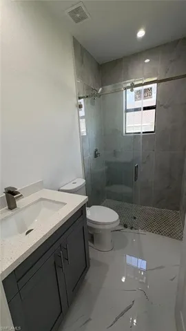 Full bath with a stall shower, marble finish floor, visible vents, and vanity