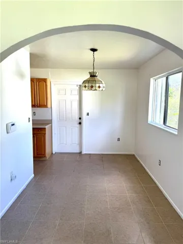 Unfurnished dining area featuring arched walkways and baseboards