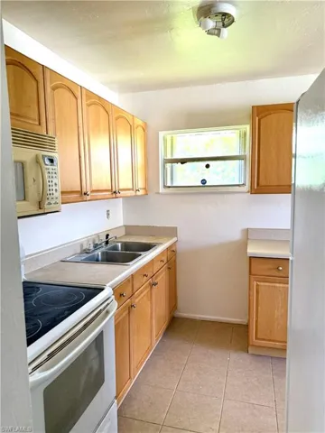 Kitchen featuring white appliances, light tile patterned floors, and light countertops