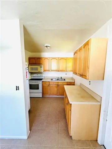 Kitchen with light countertops, white appliances, light tile patterned floors, and a textured ceiling