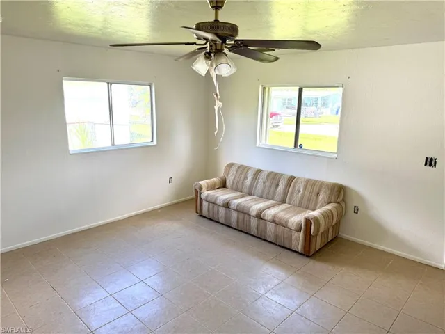 Living area featuring healthy amount of natural light, a textured ceiling, light tile patterned floors, and a ceiling fan