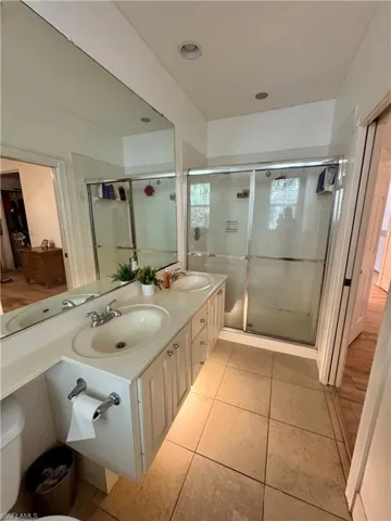 Full bath with double vanity, light tile patterned flooring, a shower stall, and recessed lighting