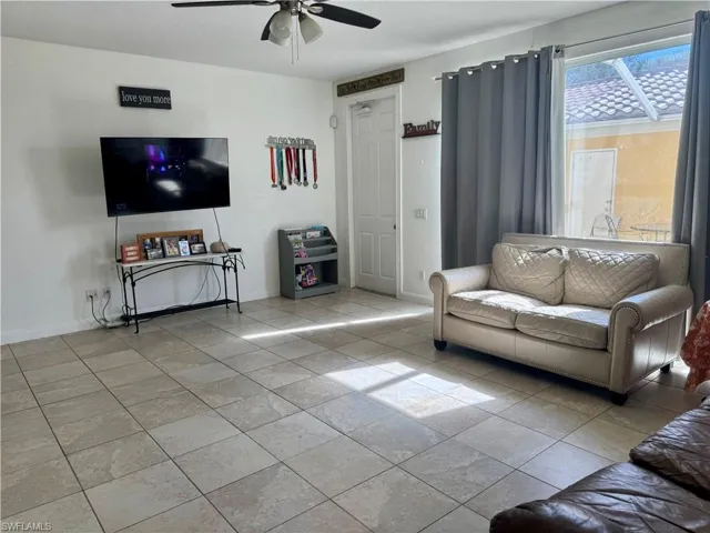 Living area featuring a ceiling fan and light tile patterned floors
