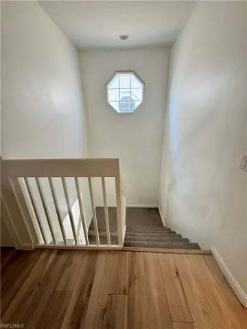 Stairway with wood finished floors and baseboards