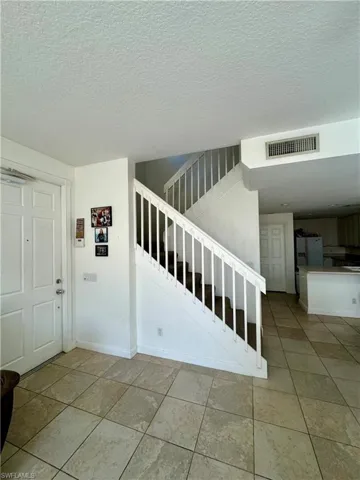Stairway featuring tile patterned floors and a textured ceiling