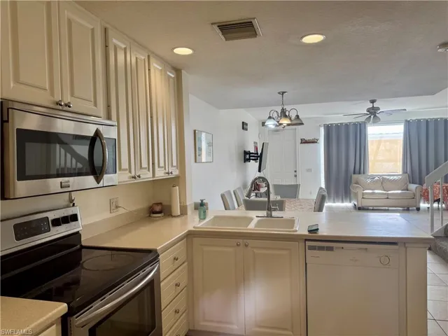Kitchen with appliances with stainless steel finishes, open floor plan, light countertops, a peninsula, and decorative light fixtures