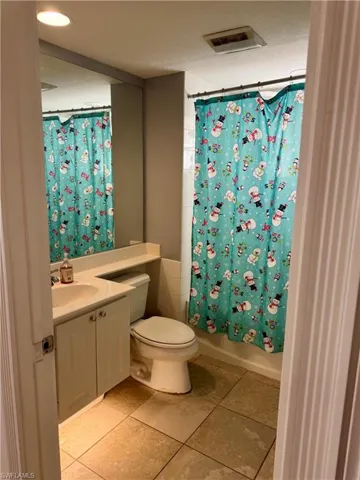 Full bath with vanity, shower / bathtub combination with curtain, and light tile patterned floors
