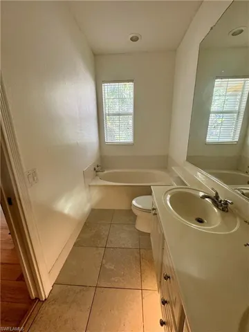 Bathroom featuring vanity, a bath, and light tile patterned floors