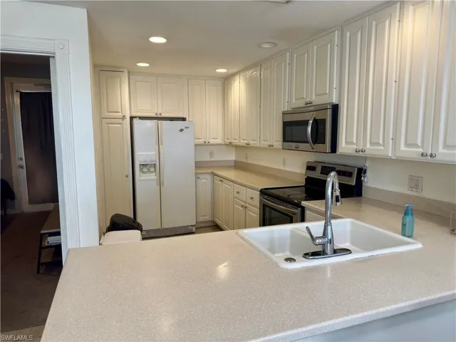 Kitchen featuring stainless steel appliances, light countertops, white cabinets, and recessed lighting