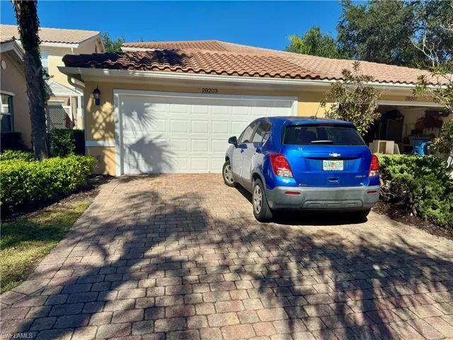 View of front of property featuring decorative driveway, a tiled roof, a garage, and stucco siding