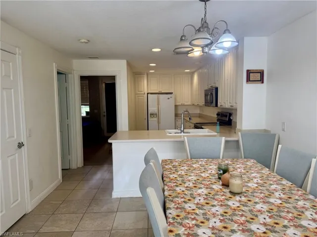 Dining area with light tile patterned floors, recessed lighting, and a chandelier