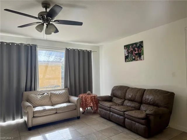 Living room featuring ceiling fan, tile patterned flooring, and a textured ceiling