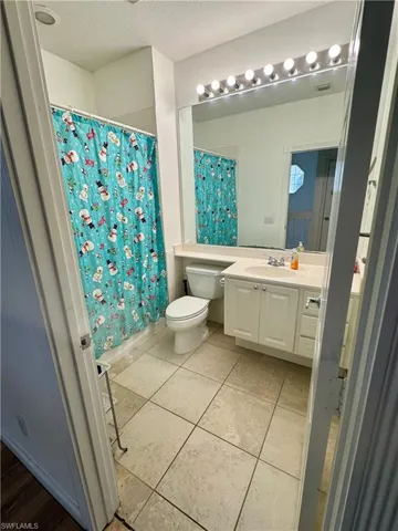 Full bathroom featuring vanity, a textured ceiling, light tile patterned floors, and shower / tub combo with curtain