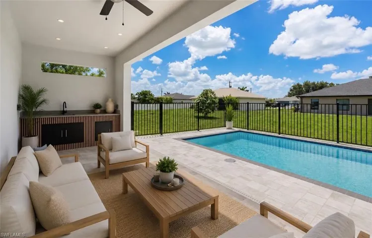 Covered outdoor living space featuring an integrated outdoor kitchen with a dark countertop and paneled cabinetry