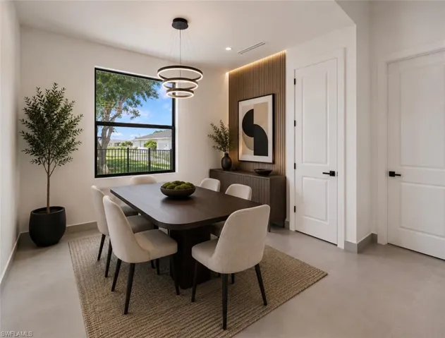 Modern dining space featuring a large window, contemporary circular pendant lighting, wood-paneled accent wall with integrated backlighting, a dark wood dining table, and light-toned flooring