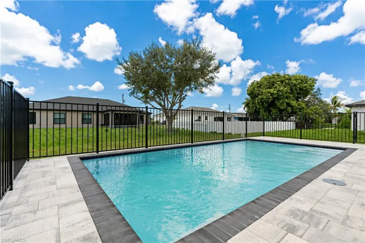 Rectangular swimming pool featuring a dark perimeter tile and light-toned paver decking