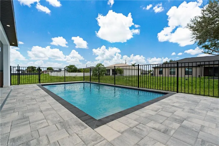 Rectangular inground pool with dark coping, surrounded by a paver patio