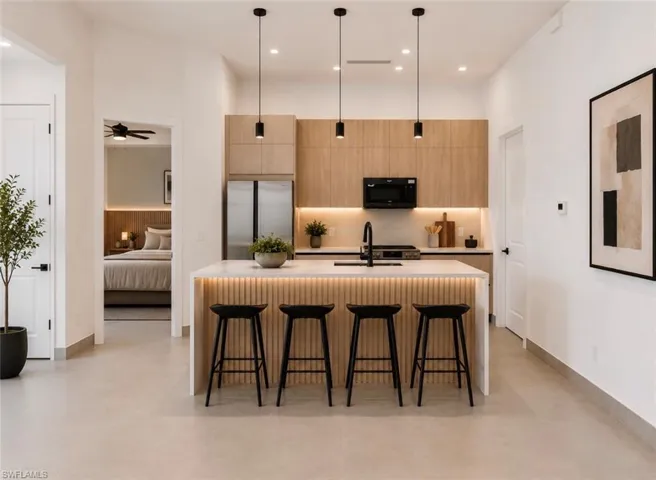 Modern kitchen featuring light wood-finish cabinetry, a large center island with integrated seating, and sleek pendant lighting