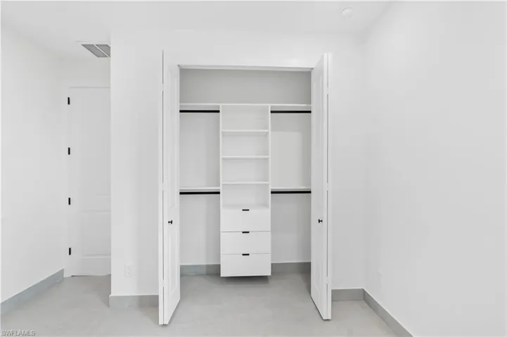 Integrated closet system featuring adjustable shelving and built-in drawers, complemented by white bi-fold doors