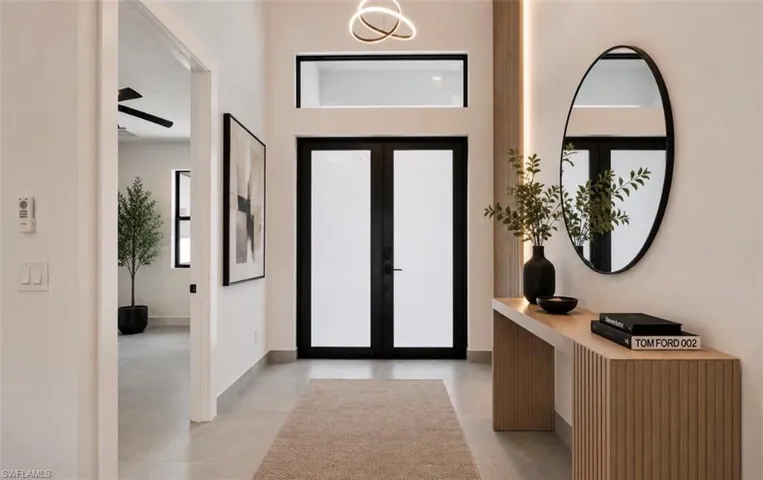 Entry foyer featuring a contemporary chandelier, transom window, and dual entry doors with frosted glass panels