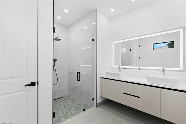 Contemporary bathroom featuring a spacious glass-enclosed shower with pebble-tile flooring and marble-look wall tiling
