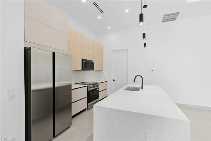 Modern kitchen featuring an expansive island with an undermount sink and matte black faucet