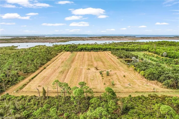 View of rural area featuring a nearby body of water and large plots for crops