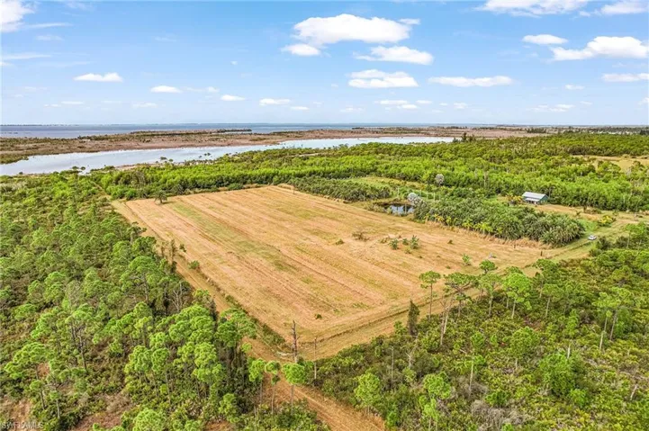 Aerial view of sparsely populated area with a large body of water and large plots for crops