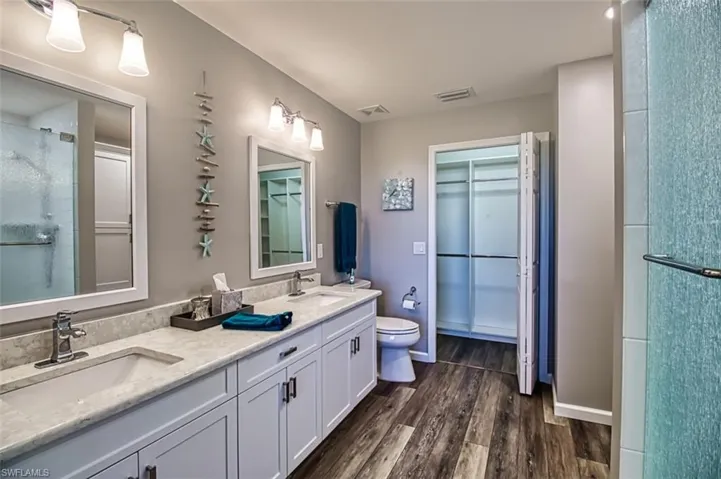 Bathroom with wood finished floors, a sink, and visible vents