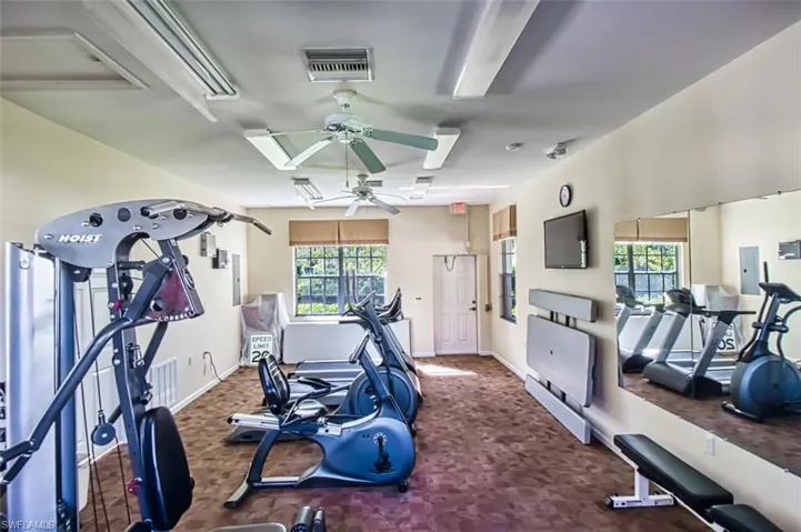 Exercise room featuring baseboards, a ceiling fan, visible vents, and electric panel