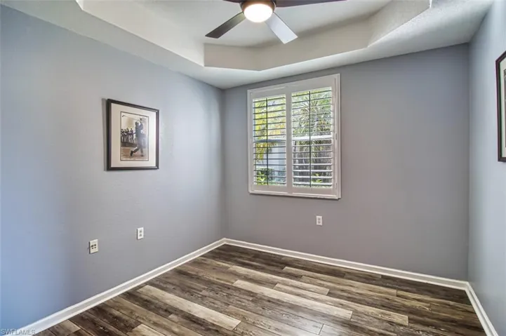 Spare room featuring ceiling fan, baseboards, a raised ceiling, and wood finished floors