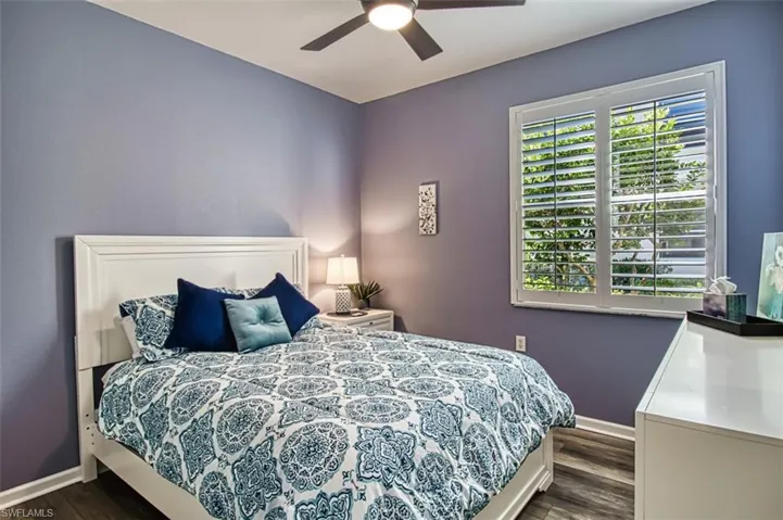 Bedroom with dark wood-style flooring, ceiling fan, and baseboards
