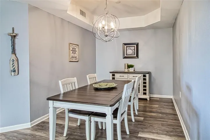 Dining room featuring a chandelier, a tray ceiling, dark wood-type flooring, and baseboards