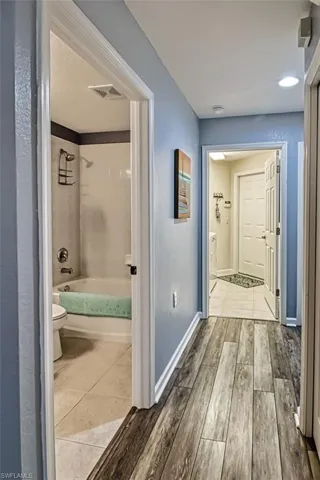 Corridor featuring baseboards, visible vents, and wood finished floors