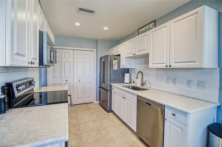 Kitchen with visible vents, stainless steel appliances, light countertops, white cabinetry, and a sink