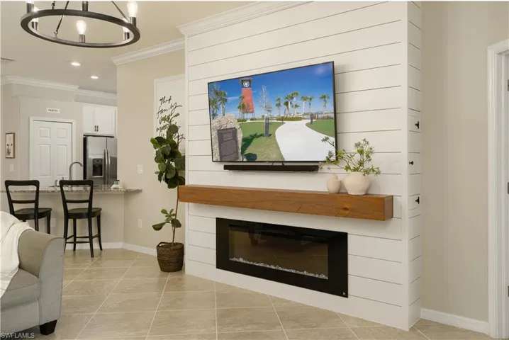 Tiled living room featuring crown molding and a farmhouse style chandelier