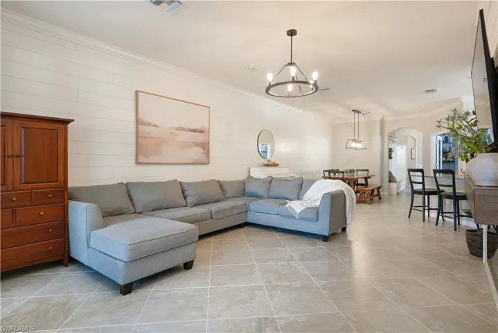Tiled living room featuring a notable chandelier and ornamental molding