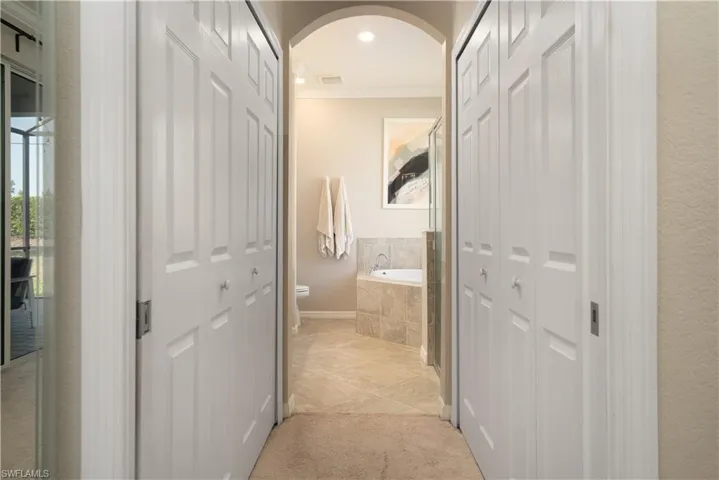 Hallway featuring light colored carpet, dual walk in closets