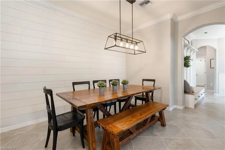 Dining area with ornamental molding and light tile floors