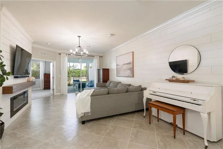 Living room with crown molding, light tile floors, and an inviting chandelier