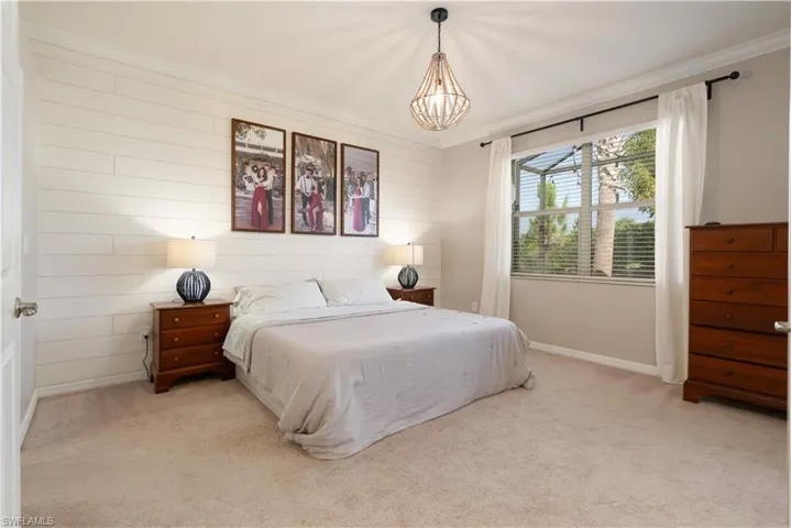 Primary Bedroom featuring light colored carpet, a boho style chandelier, and crown molding