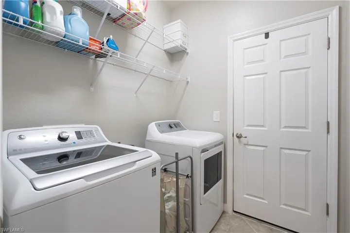 Washroom featuring washer and clothes dryer and light tile floors