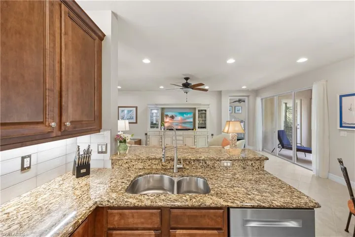 Kitchen with sink, ceiling fan, tasteful backsplash, light stone countertops, and light tile patterned flooring